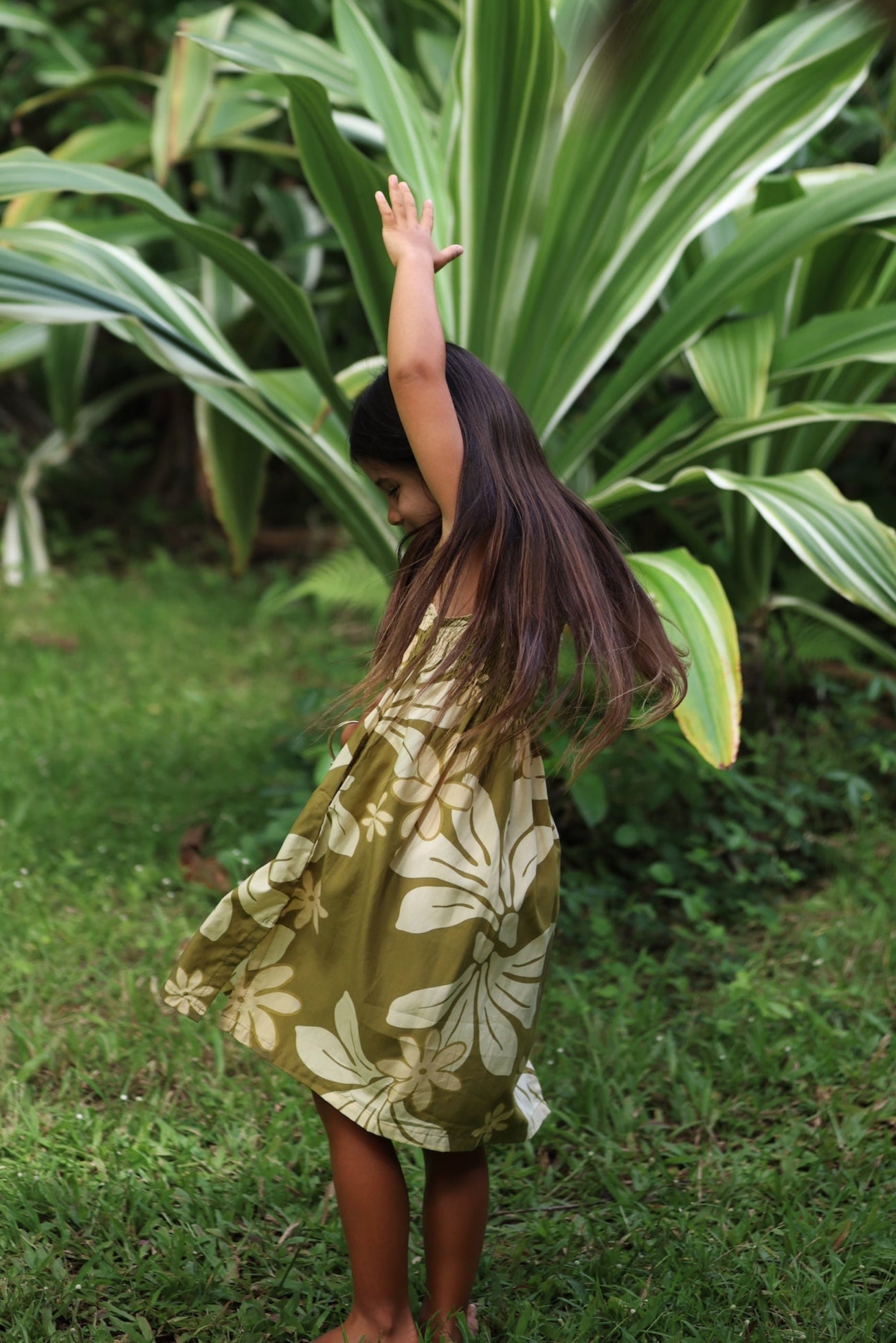 little girl wearing spaghetti strap dress in green print with naupaka pattern