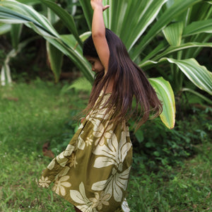 little girl wearing spaghetti strap dress in green print with naupaka pattern
