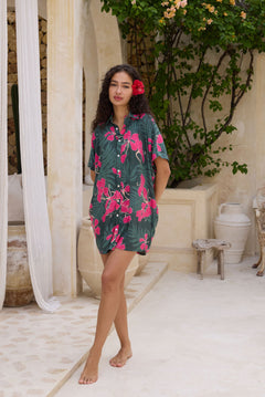 woman with brown hair wearing a dark green button-up, oversized shirt dress with fern and ginger print