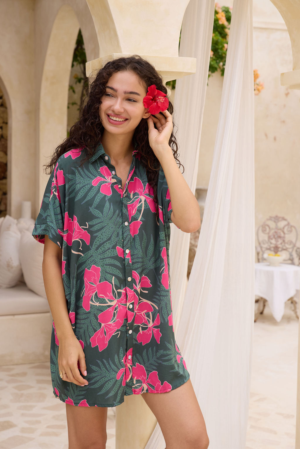 woman with brown hair wearing a dark green button-up, oversized shirt dress with fern and ginger print