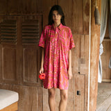 A woman with dark hair wears a YIREH collared, button-up dress. It is the Kaimana Dress in the Garden 'Awapuhi print. 
