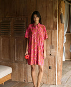 A woman with dark hair wears a YIREH collared, button-up dress. It is the Kaimana Dress in the Garden 'Awapuhi print. 