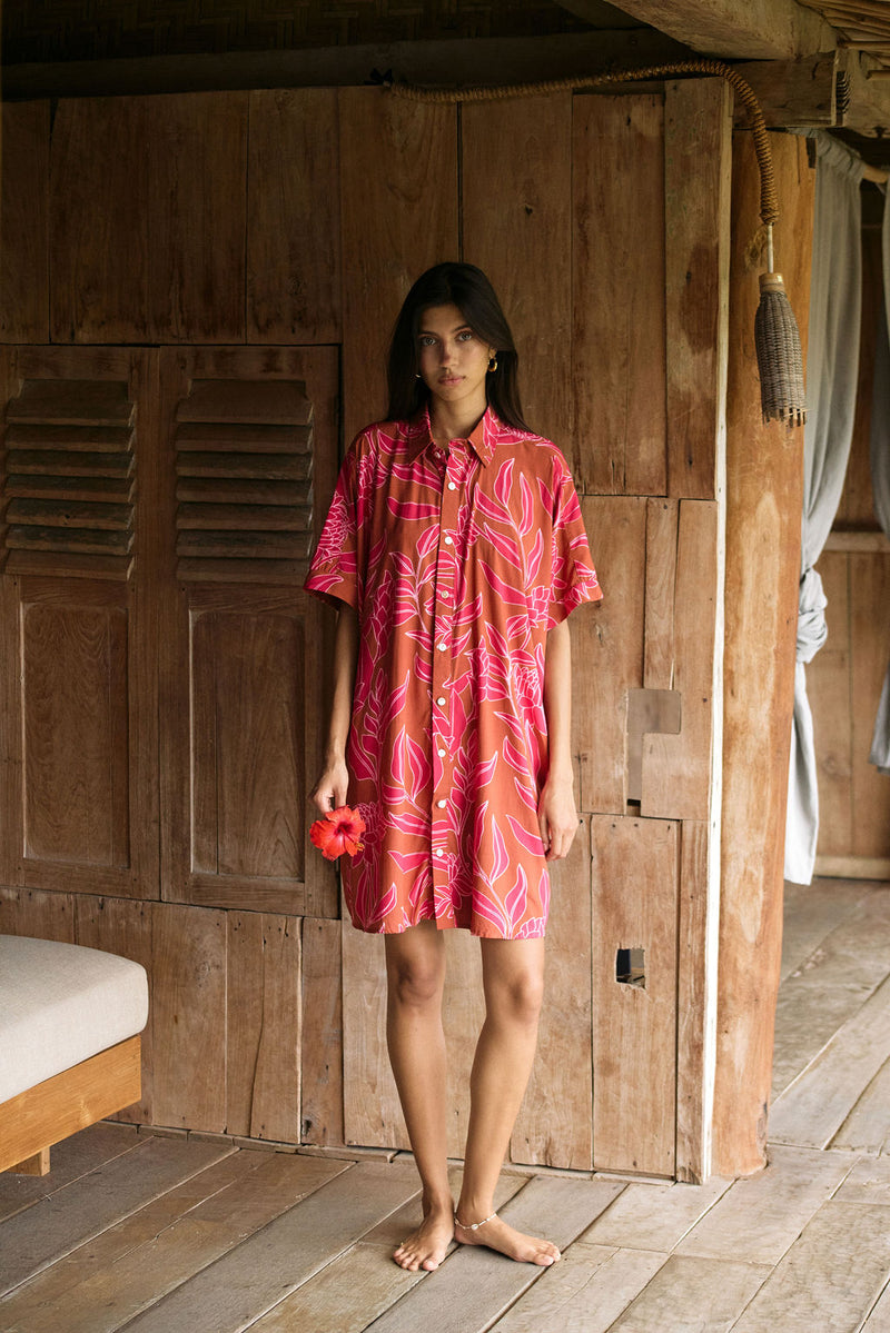 A woman with dark hair wears a YIREH collared, button-up dress. It is the Kaimana Dress in the Garden 'Awapuhi print. 