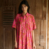 A woman with dark hair wears a YIREH collared, button-up dress. It is the Kaimana Dress in the Garden 'Awapuhi print. 