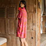 A woman with dark hair wears a YIREH collared, button-up dress. It is the Kaimana Dress in the Garden 'Awapuhi print. 