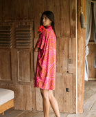 A woman with dark hair wears a YIREH collared, button-up dress. It is the Kaimana Dress in the Garden 'Awapuhi print. 