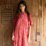 A woman with dark hair wears a YIREH collared, button-up dress. It is the Kaimana Dress in the Garden 'Awapuhi print. 