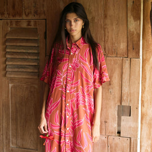 A woman with dark hair wears a YIREH collared, button-up dress. It is the Kaimana Dress in the Garden 'Awapuhi print. 
