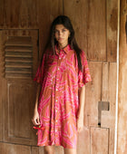 A woman with dark hair wears a YIREH collared, button-up dress. It is the Kaimana Dress in the Garden 'Awapuhi print. 