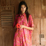 A woman with dark hair wears a YIREH collared, button-up dress. It is the Kaimana Dress in the Garden 'Awapuhi print. 