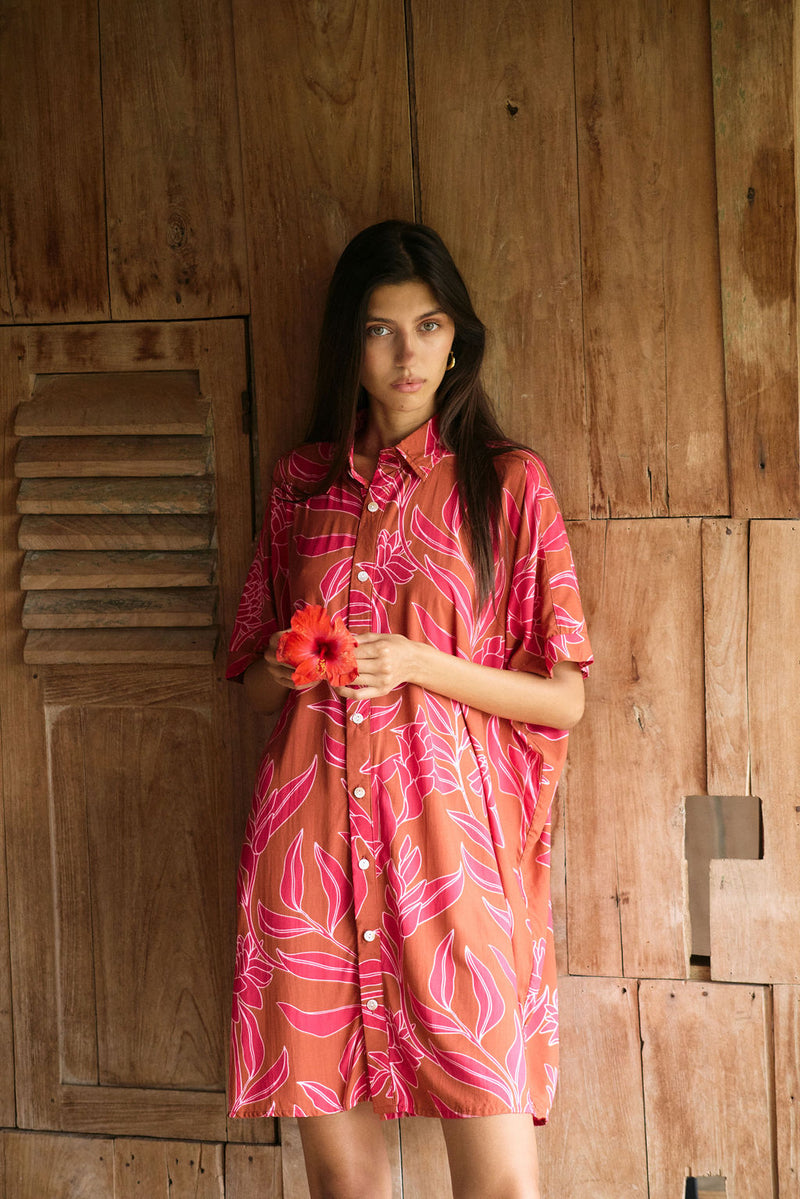 A woman with dark hair wears a YIREH collared, button-up dress. It is the Kaimana Dress in the Garden 'Awapuhi print. 