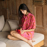 A woman with dark hair wears a YIREH collared, button-up dress. It is the Kaimana Dress in the Garden 'Awapuhi print. 