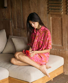 A woman with dark hair wears a YIREH collared, button-up dress. It is the Kaimana Dress in the Garden 'Awapuhi print. 