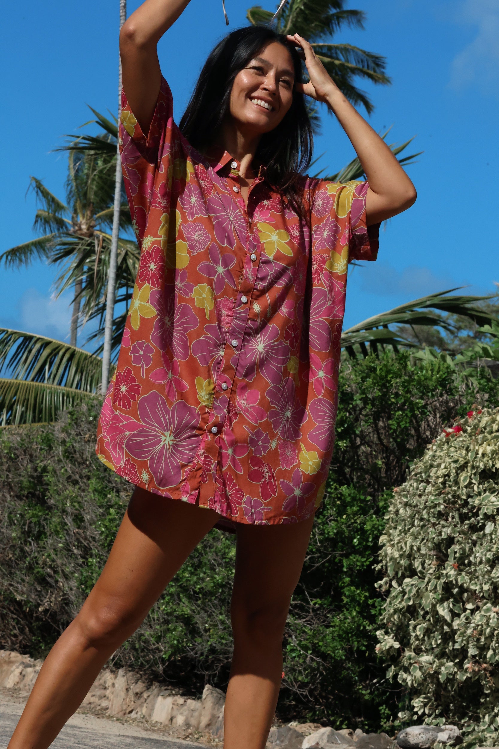 woman wearing terracotta colored button up shirt dress with large purple and yellow flower pattern