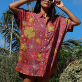 woman wearing terracotta colored button up shirt dress with large purple and yellow flower pattern