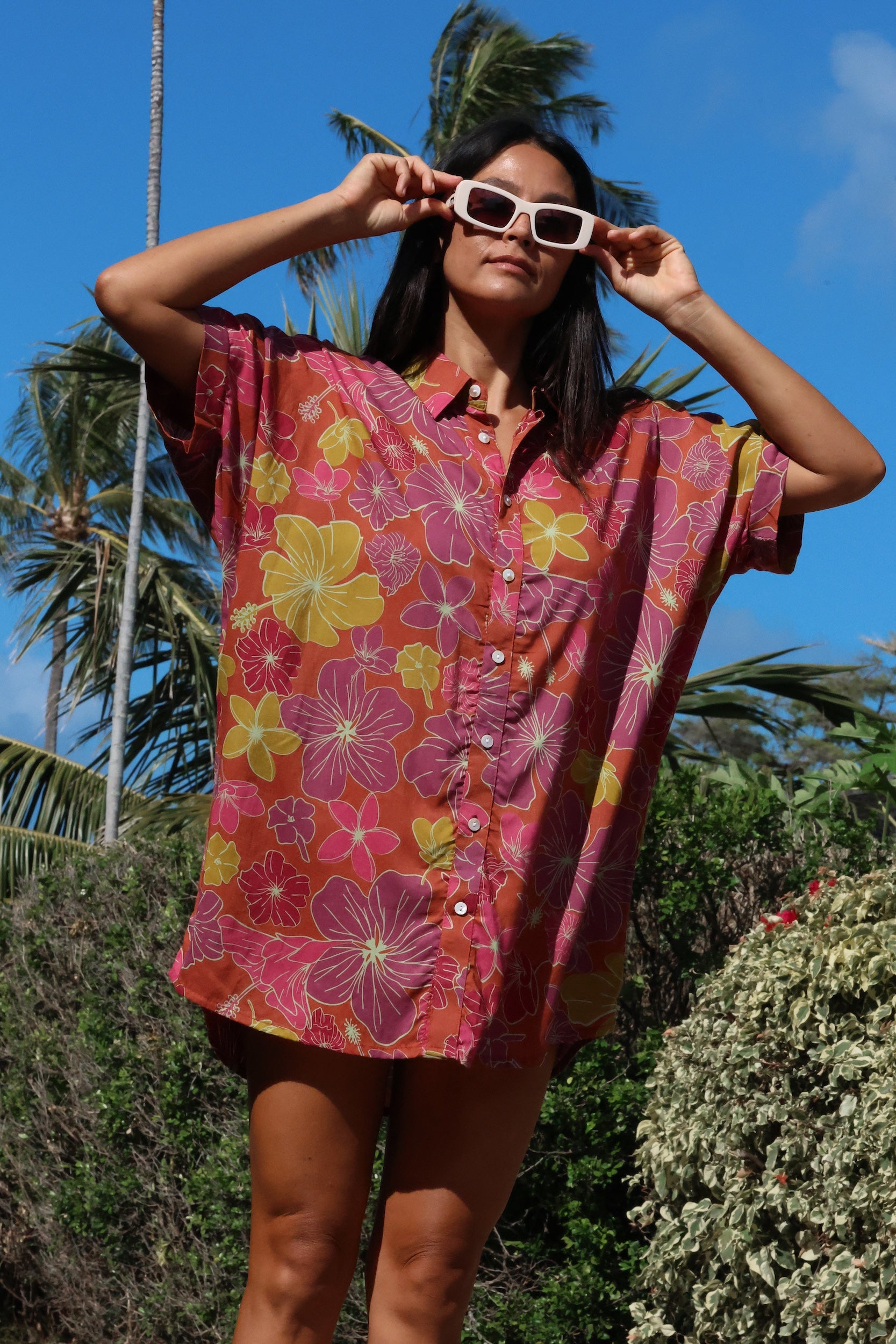 woman wearing terracotta colored button up shirt dress with large purple and yellow flower pattern