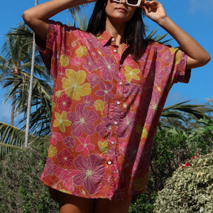 woman wearing terracotta colored button up shirt dress with large purple and yellow flower pattern