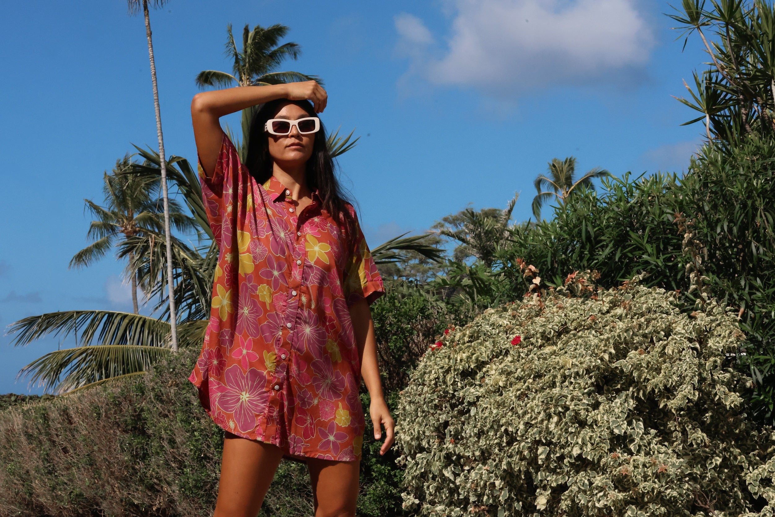 woman wearing terracotta colored button up shirt dress with large purple and yellow flower pattern