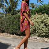 woman wearing terracotta colored button up shirt dress with large purple and yellow flower pattern