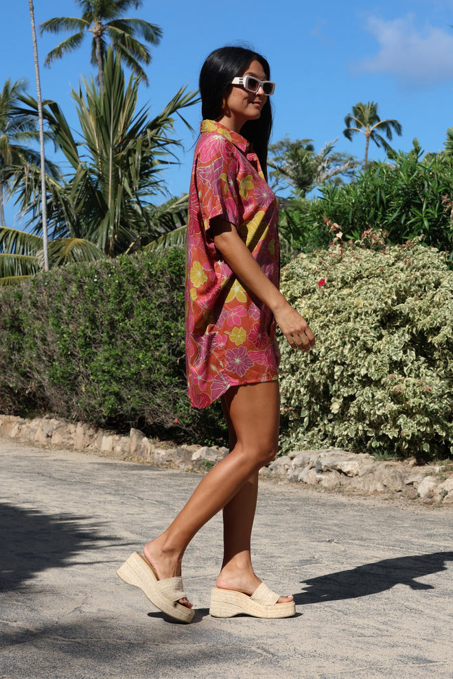 woman wearing terracotta colored button up shirt dress with large purple and yellow flower pattern
