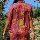 woman wearing terracotta colored button up shirt dress with large purple and yellow flower pattern