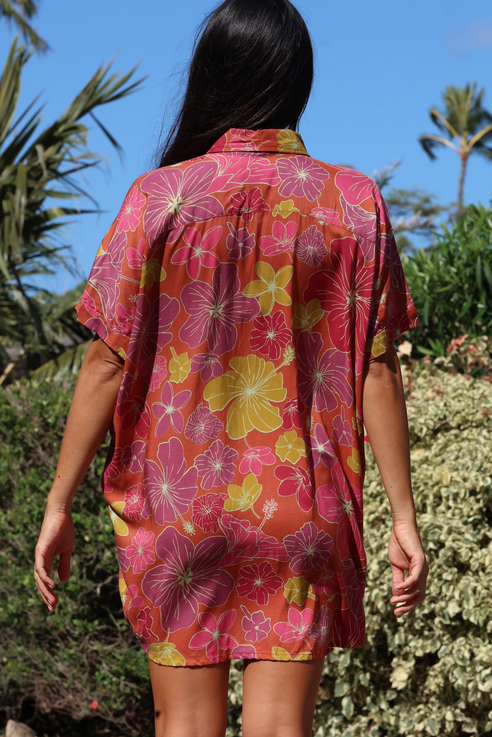 woman wearing terracotta colored button up shirt dress with large purple and yellow flower pattern