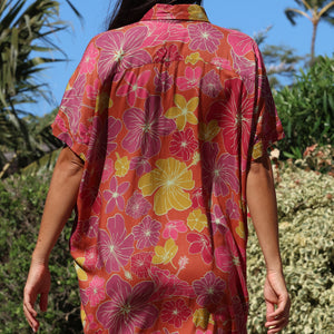 woman wearing terracotta colored button up shirt dress with large purple and yellow flower pattern