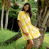 woman wearing a bright green button up dress with orchid print 