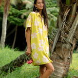woman wearing a bright green button up dress with orchid print 