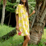 woman wearing a bright green button up dress with orchid print 
