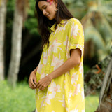 woman wearing a bright green button up dress with orchid print 