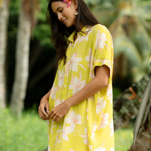 woman wearing a bright green button up dress with orchid print 