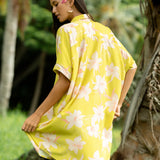 woman wearing a bright green button up dress with orchid print 