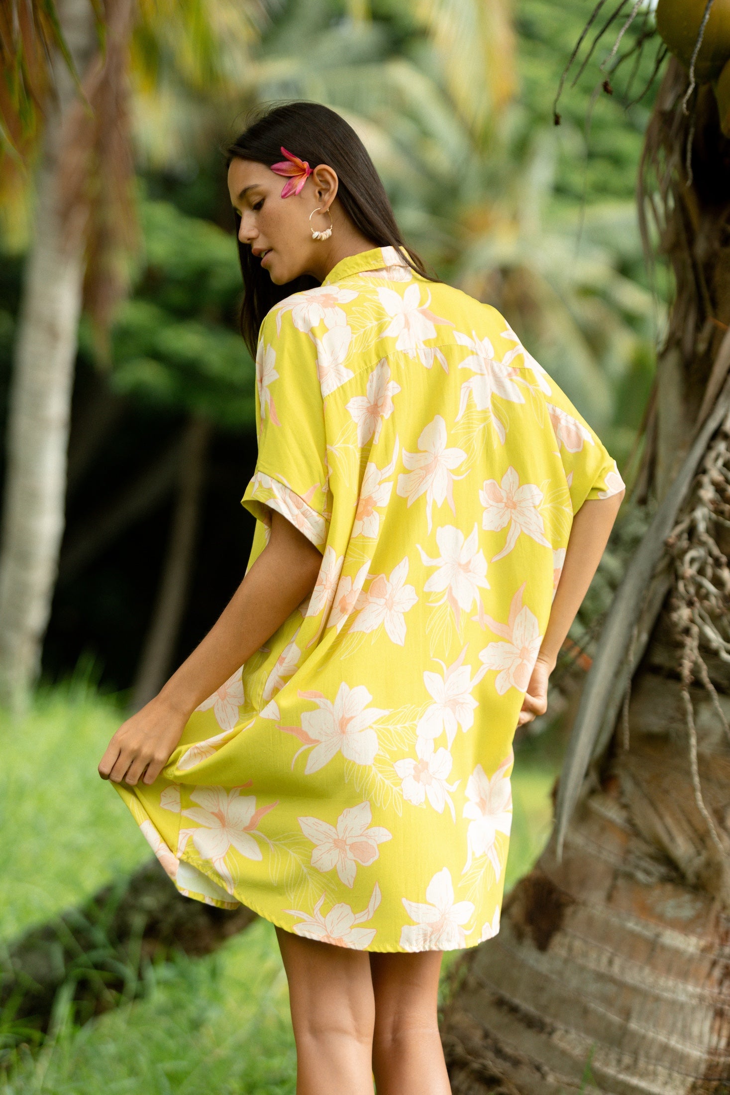 woman wearing a bright green button up dress with orchid print 