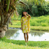 woman wearing a bright green button up dress with orchid print 