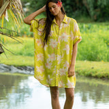 woman wearing a bright green button up dress with orchid print 