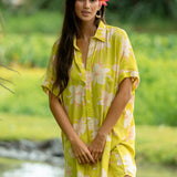 woman wearing a bright green button up dress with orchid print 
