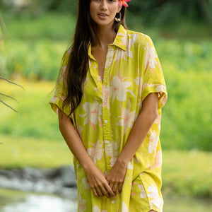 woman wearing a bright green button up dress with orchid print 