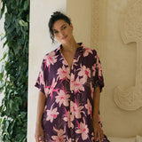 woman wearing an oversized button up shirt dress in dark purple color with orchid print