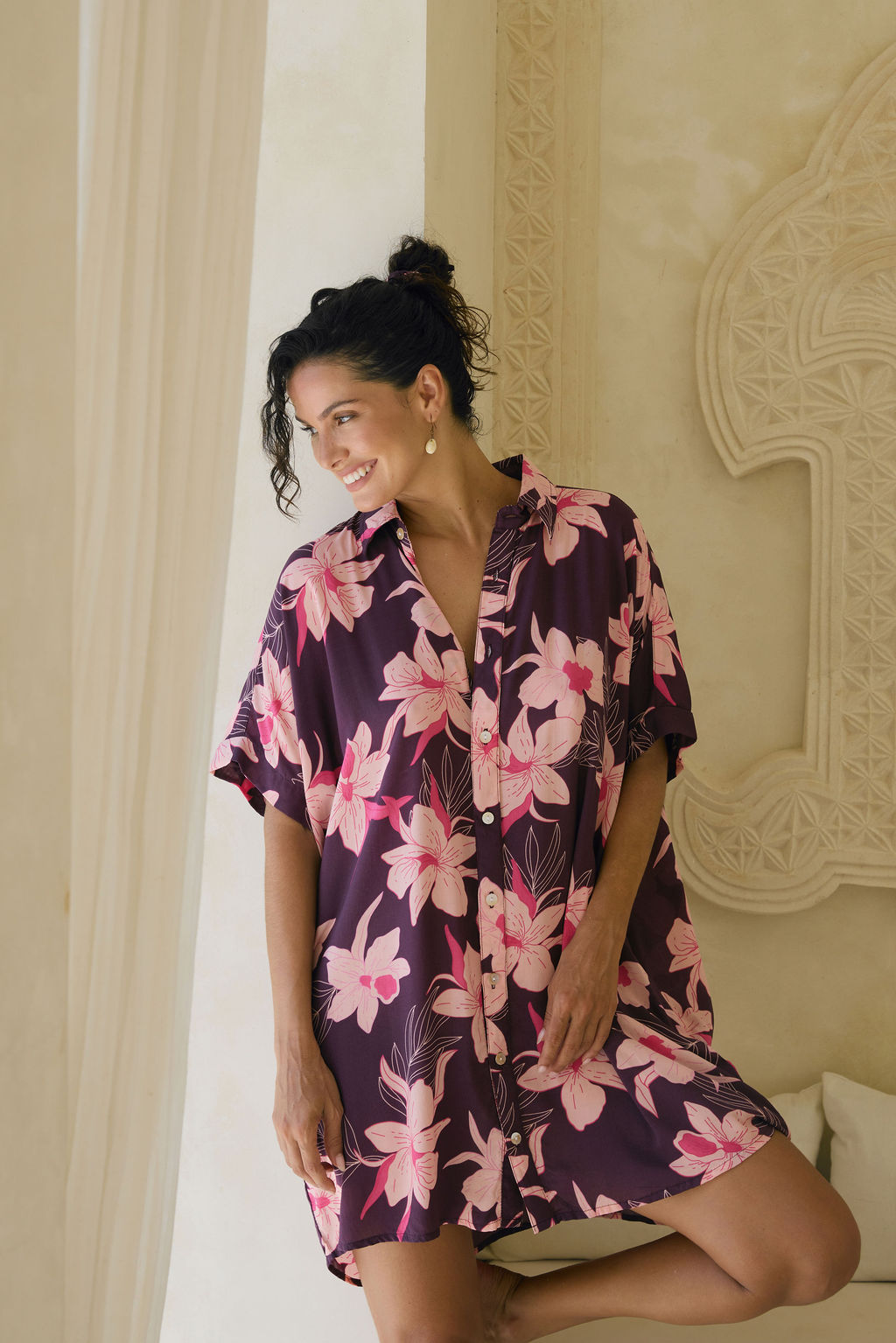 woman wearing an oversized button up shirt dress in dark purple color with orchid print
