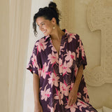 woman wearing an oversized button up shirt dress in dark purple color with orchid print