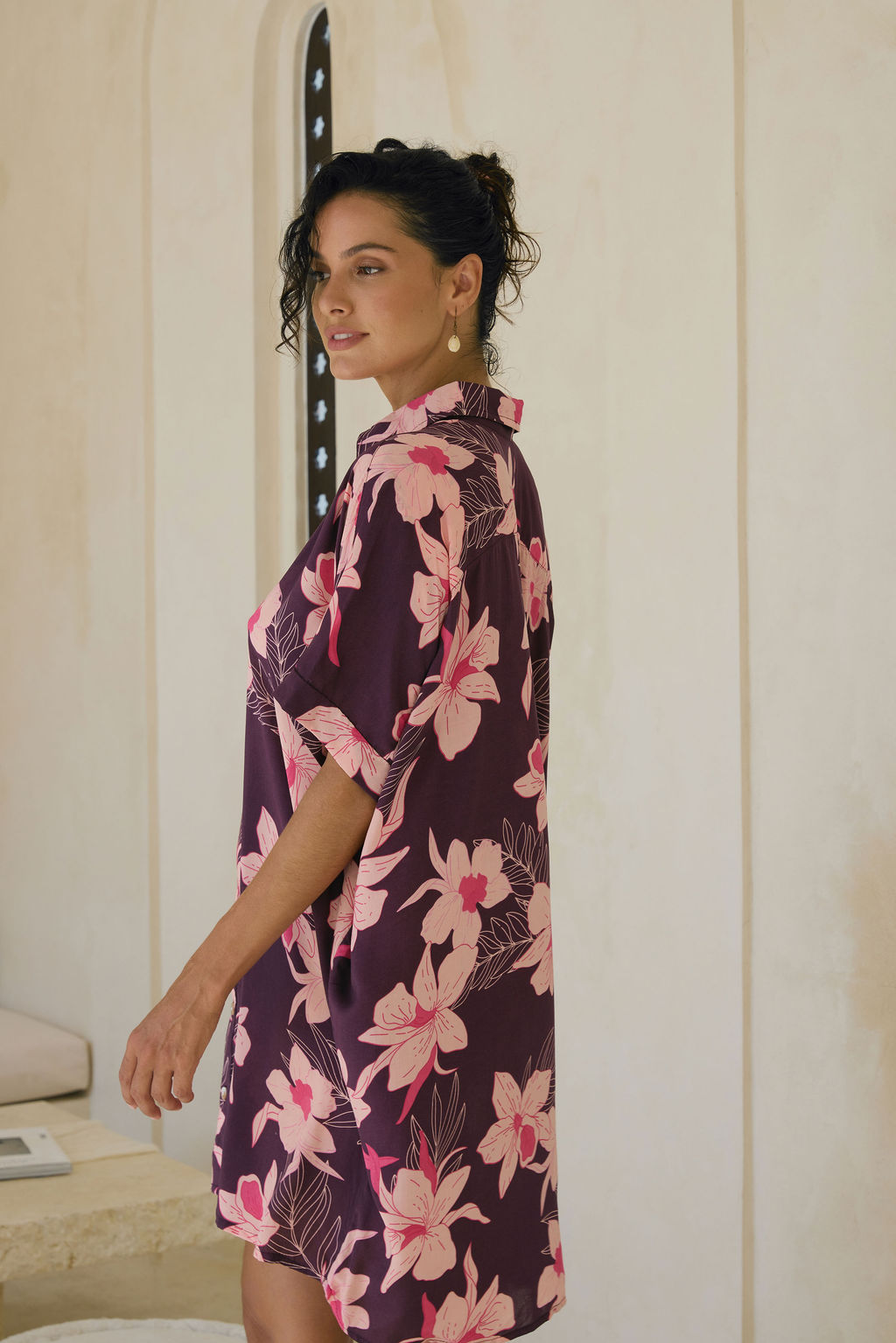 woman wearing an oversized button up shirt dress in dark purple color with orchid print