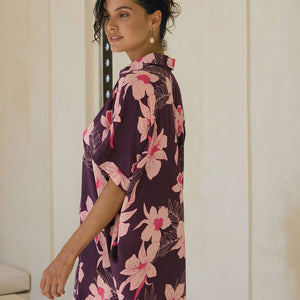 woman wearing an oversized button up shirt dress in dark purple color with orchid print