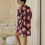 woman wearing an oversized button up shirt dress in dark purple color with orchid print