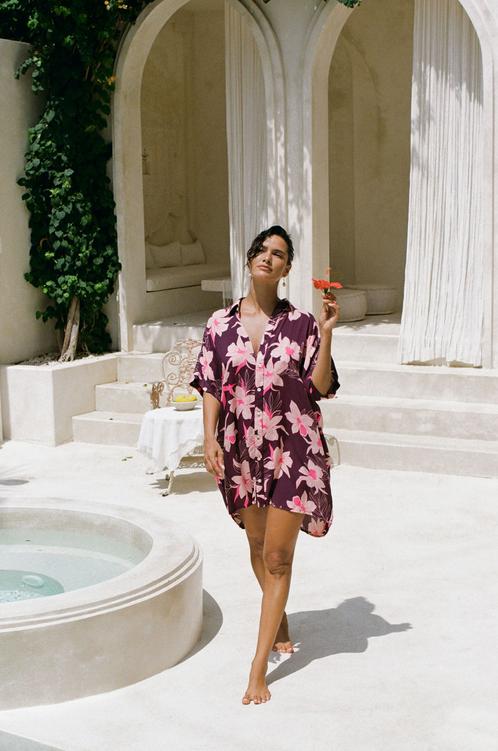 woman wearing an oversized button up shirt dress in dark purple color with orchid print
