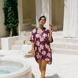 woman wearing an oversized button up shirt dress in dark purple color with orchid print