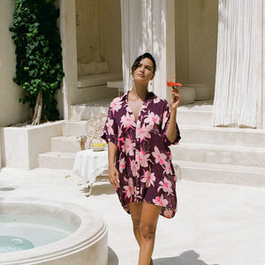 woman wearing an oversized button up shirt dress in dark purple color with orchid print