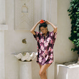 woman wearing an oversized button up shirt dress in dark purple color with orchid print