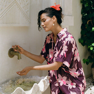 woman wearing an oversized button up shirt dress in dark purple color with orchid print