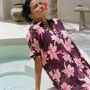 woman wearing an oversized button up shirt dress in dark purple color with orchid print
